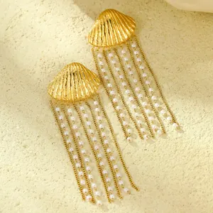 Macro detail of gold seashell earrings with pearl tassels on a natural rock surface