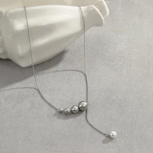 Vue détaillée d'un collier en Y argenté avec des billes gris mat et une perle blanche