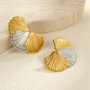 Makro-Detail von fächerförmigen Ohrsteckern mit Gold-Silber-Bicolor-Metalloberfläche