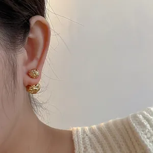 Gros plan de boucles d'oreilles boules dorées à texture irrégulière style lave fondue