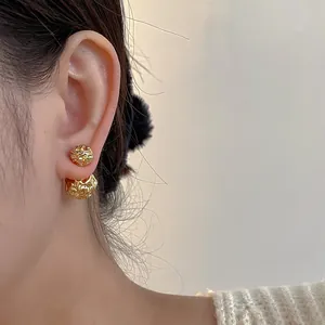 Vue macro de boucles d'oreilles à double sphère dorée texturée portées à l'oreille