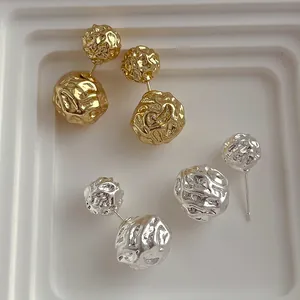 Vue détaillée de boucles d'oreilles boules en métal irrégulières martelées en or et argent