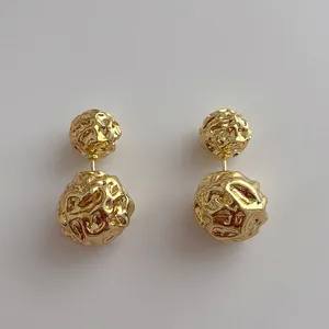 Détail de boucles d'oreilles boules dorées à texture irrégulière et design double face