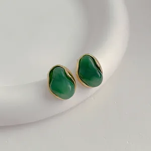 Orecchini minimalisti in resina verde con bordo dorato su vassoio in ceramica