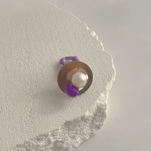 Makro-Detail des unregelmäßigen Muschelrings mit weißer Perle und lila Perlen auf Stein