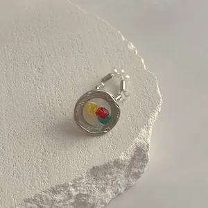 Detail eines unregelmäßigen Muschelrings mit bunten Harzperlen auf Steinhintergrund