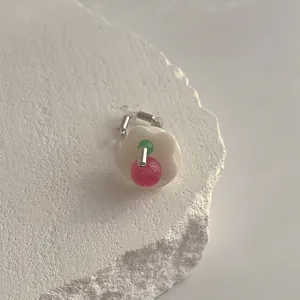 Detail eines Perlenblumenrings mit rosa und grünen Perlen auf weißem Naturstein