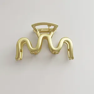 Close-up of matte gold wave-shaped metal hair claw clip with durable spring and teeth