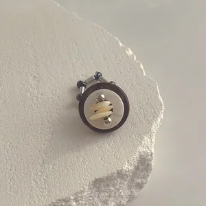 Makro-Detail des unregelmäßigen Muschelrings mit Holzring und silbernen Metallperlen