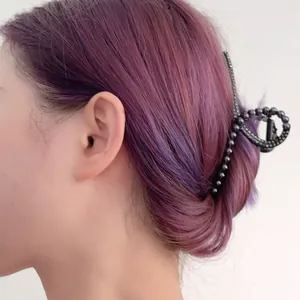Detailopname van een metalen haarklem met kattenoogkralen in paars geverfd haar