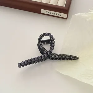Detail van een elegante zwarte haarklem met imitatieparels en grijze strassteentjes