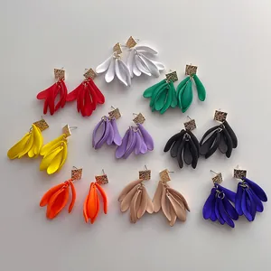 Flat lay of nine pairs of colorful oversized matte petal drop earrings with gold studs