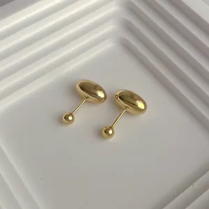 Macro shot of minimalist gold bean stud earrings with screw ball backings on white display