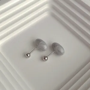 Macro shot of minimalist marble texture stud earrings with silver metal base detail