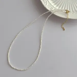 Detailed view of 2mm shell pearl necklace featuring gold lobster clasp and extension chain