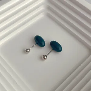 Minimalist dark green oval stud earrings with silver screw backs on white tray