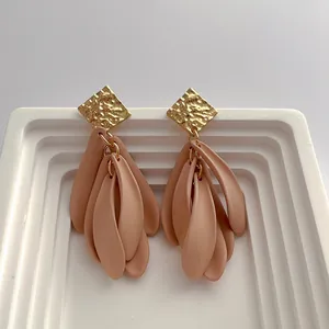 Detail of gold hammered square studs with matte nude resin petal fringe pendants