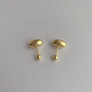 Close-up of minimalist gold-plated bean stud earrings with polished smooth texture