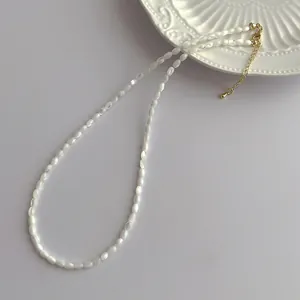 Close-up of white shell bead necklace featuring golden lobster clasp and adjustable chain