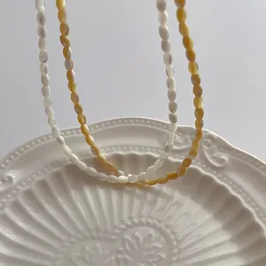 Close-up of pearl white and amber oval shell beads on an elegant ceramic plate