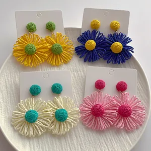 Detail van handgemaakte raffia madeliefjes oorbellen op displaykaarten