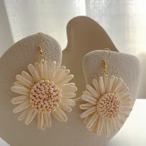 Detailansicht der handgefertigten Bast-Sonnenblumenohrringe auf einem Display