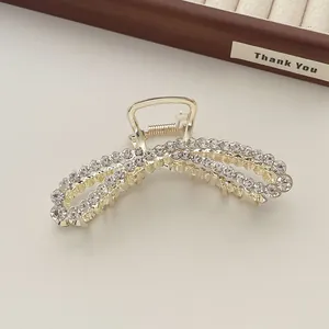Close-up of a gold metal hair claw clip with double-layered bow design and sparkling zircons