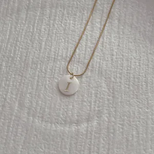 Detail of a natural shell letter I pendant on a golden snake chain necklace