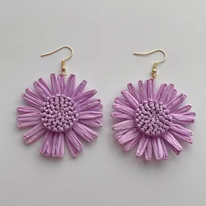 Detail der handgefertigten violetten Raffia-Sonnenblumen-Ohrringe mit Goldhaken