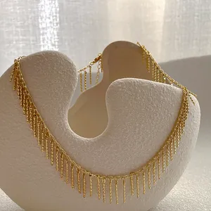 Elegante gouden franje halsketting op een getextureerde keramische schaal met minimalistisch design