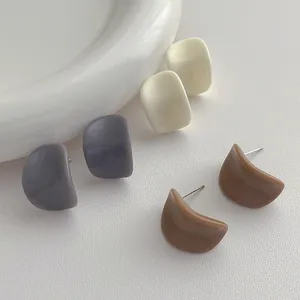 Gros plan de boucles d'oreilles en résine crème, grise et brune avec tiges en argent S925