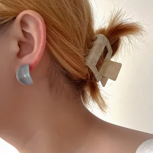 Ensemble boucles d'oreilles en résine et pince à cheveux marbrée sur un modèle