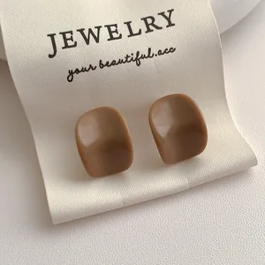 Gros plan de boucles d'oreilles minimalistes en résine brune au design irrégulier poli
