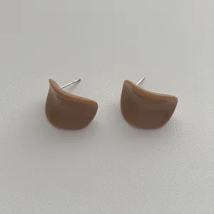 Vue macro des boucles d'oreilles en résine marron sur fond de cuir gris clair