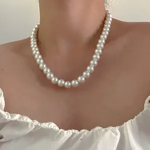 Gros plan d'un collier de perles blanches élégant porté avec un vêtement à volants