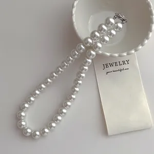 Gros plan d'un élégant collier de perles blanches à un rang avec fermoir argenté