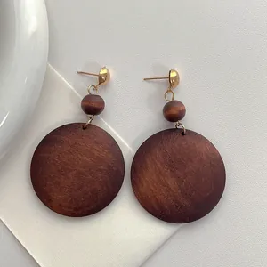 Chic oversized circular wood drop earrings with natural brown grain and gold metal studs