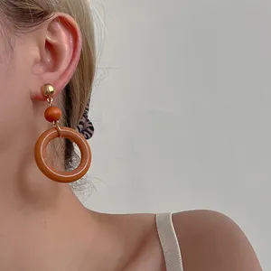 Close-up of minimalist wooden hoop earrings worn by a model in a natural side view