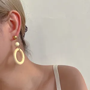 Detail shot of vintage wooden hoop earrings with metallic gold stud on a model