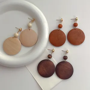 Detailed view of three pairs of wooden hoop earrings in light, tan, and dark brown finishes