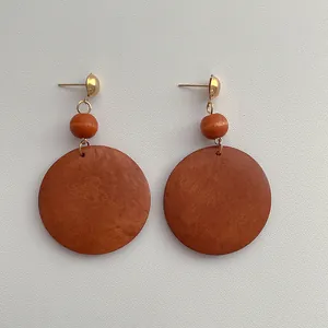 Close-up of bohemian wood hoop earrings with brown discs and gold-tone studs