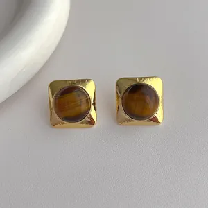 Macro detail of vintage gold square earrings featuring natural brown tiger eye stones
