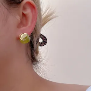 Minimalist resin and gold metal ear studs shown on model for autumn fashion style