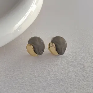 Close-up of irregular grey resin and gold metal earrings with S925 silver needles