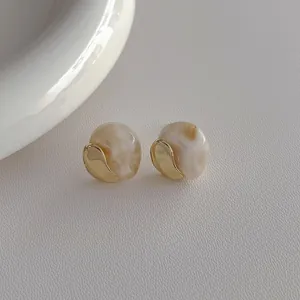 Close-up of resin marble stud earrings with gold irregular metal wrap details