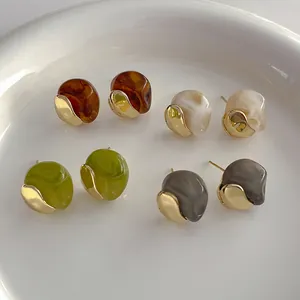 Detailed view of irregular resin earrings in amber, marble, green, and smoke grey colors