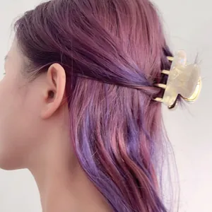 Elegant cream white acetate hair claw with golden metal teeth on purple hair