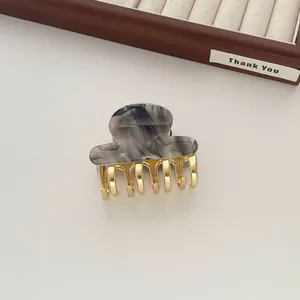 Detail of a medium acetate hair claw with grey marble pattern and golden metal teeth