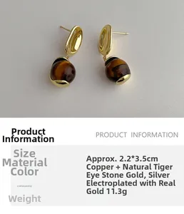 Detail view of round tiger eye stone drop earrings with gold plated copper finish