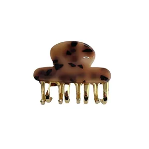 Retro tortoiseshell hair claw clip with golden metal teeth on white background
